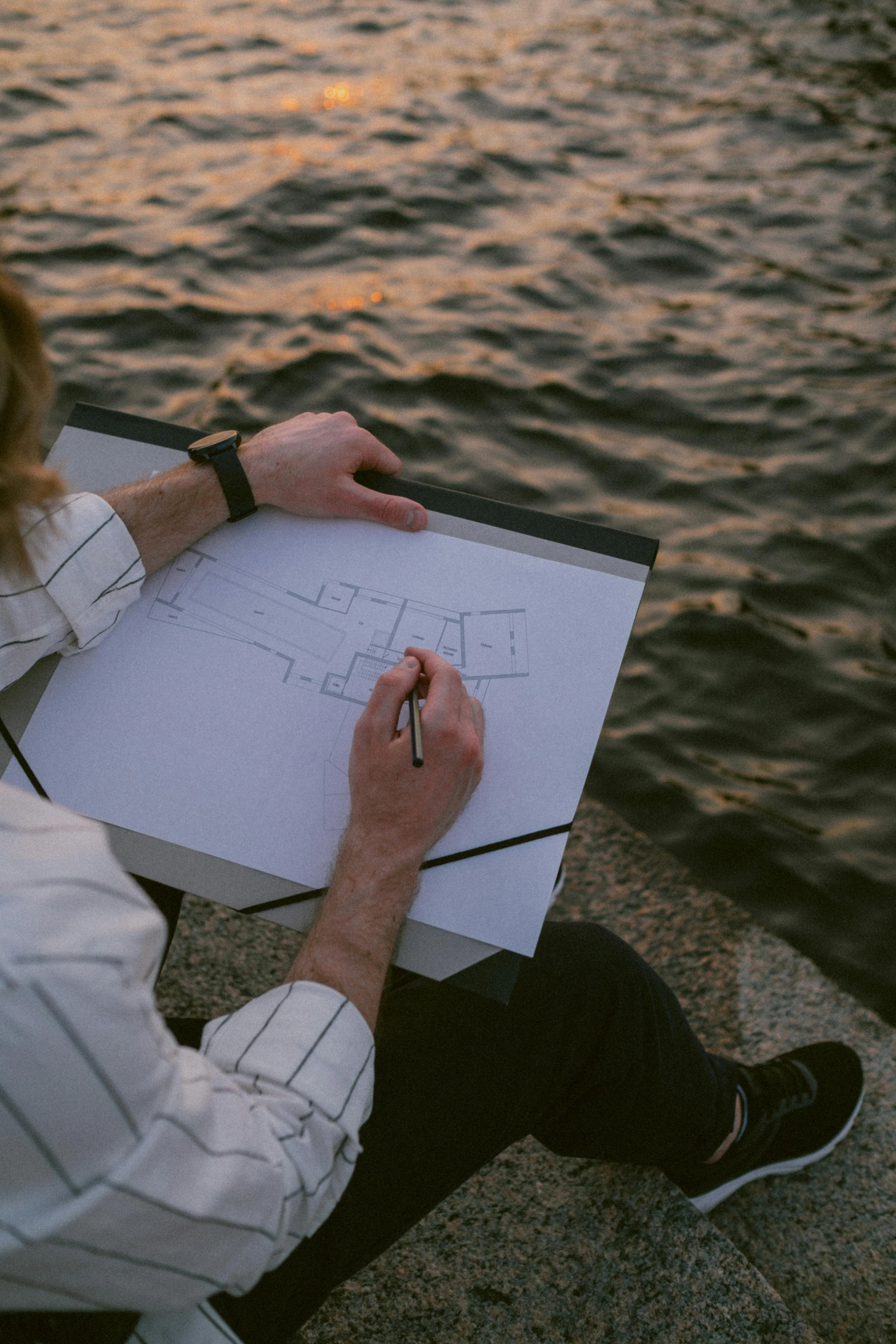 A landscape architect sketching a garden design on a blueprint.