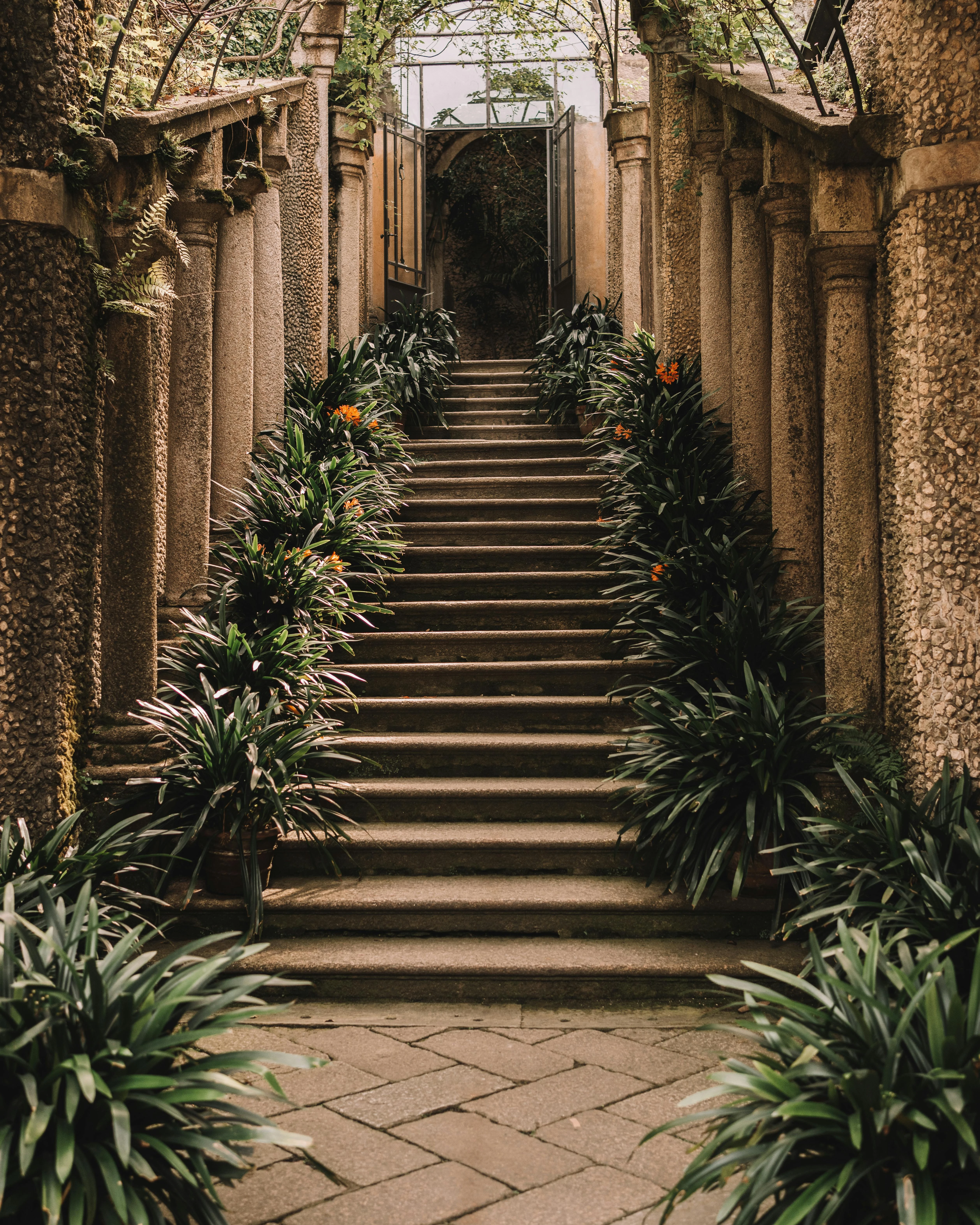 A lush garden with overflowing flower beds, roses, and a stone pathway.
